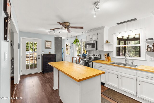 kitchen featuring wood counters, appliances with stainless steel finishes, open shelves, and a sink