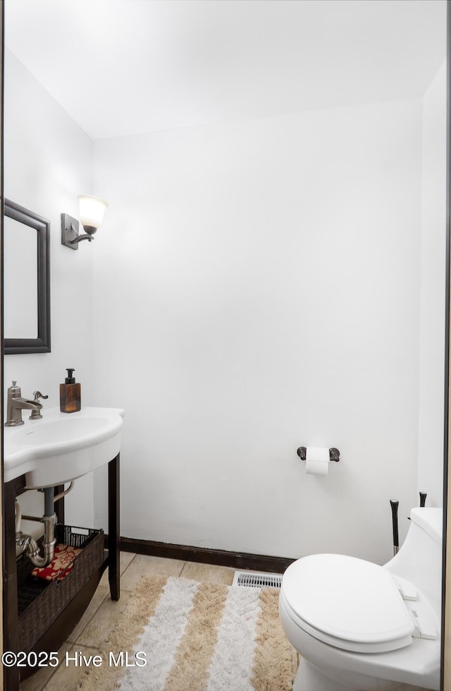 half bathroom featuring visible vents, toilet, and baseboards