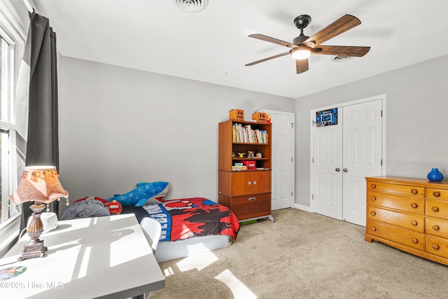 carpeted bedroom with a closet, visible vents, and a ceiling fan