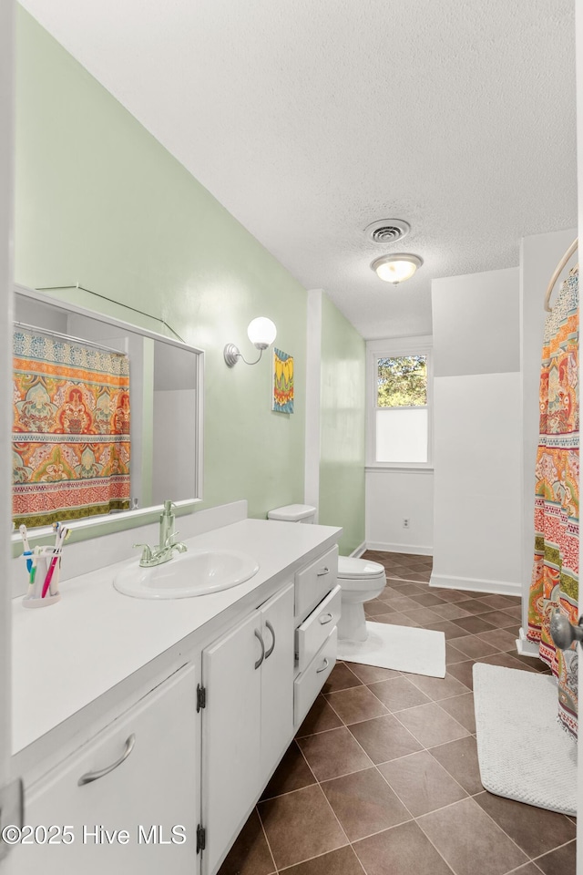 bathroom with a textured ceiling, tile patterned flooring, toilet, visible vents, and vanity