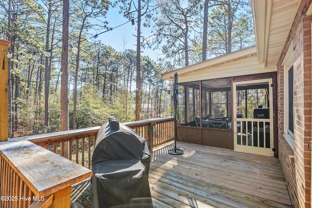 wooden terrace with a sunroom and a grill