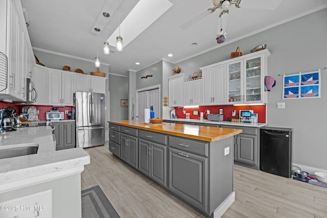 kitchen featuring gray cabinets, appliances with stainless steel finishes, white cabinetry, a kitchen island, and wood counters