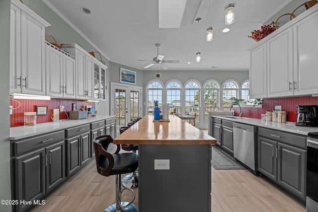 kitchen featuring white cabinetry, butcher block countertops, appliances with stainless steel finishes, and crown molding