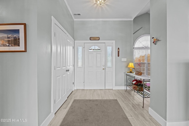 entrance foyer with baseboards, ornamental molding, visible vents, and wood tiled floor