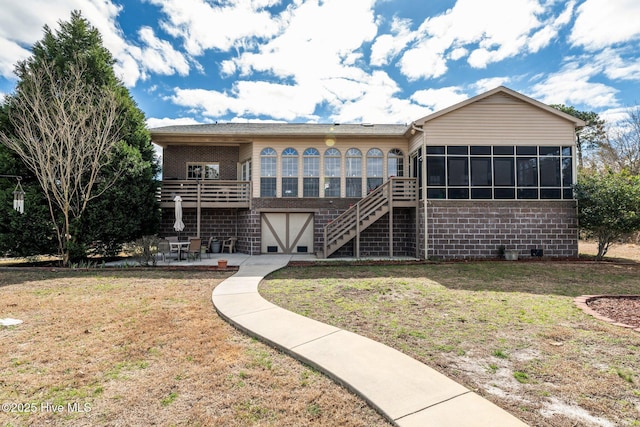 rear view of house with a sunroom, stairway, a yard, a patio area, and brick siding