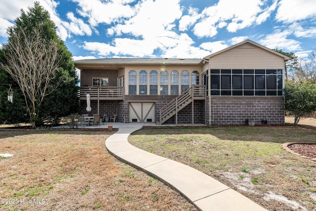 back of property with a patio, brick siding, a sunroom, stairs, and a lawn