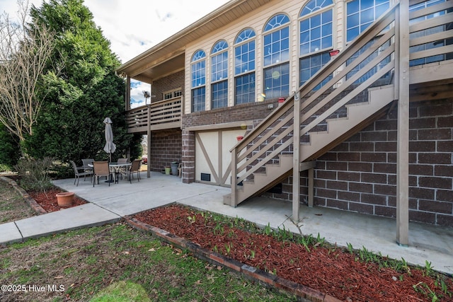 back of house featuring stairway, a patio, and brick siding