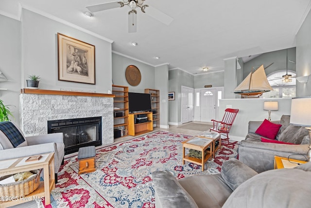 living room with ceiling fan, ornamental molding, baseboards, and a stone fireplace