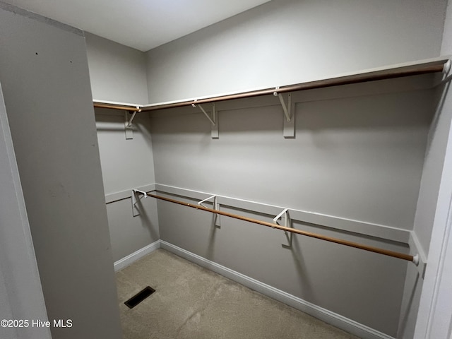 walk in closet featuring light carpet and visible vents