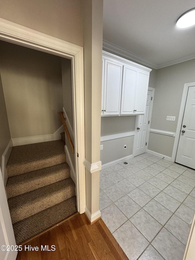 staircase with baseboards, ornamental molding, and wood finished floors