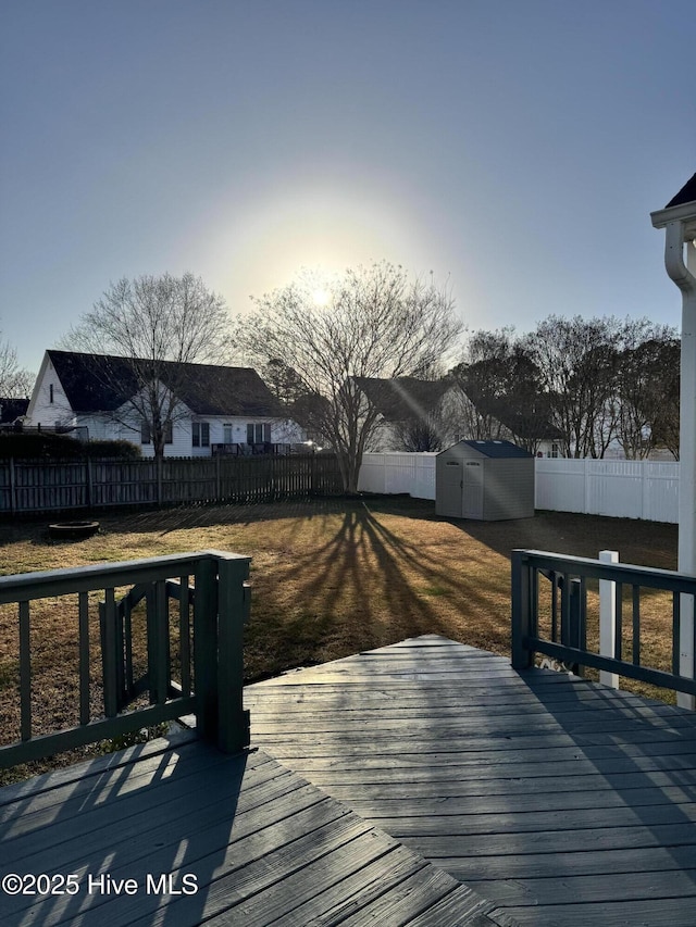 wooden deck with an outbuilding, a yard, a storage unit, and a fenced backyard