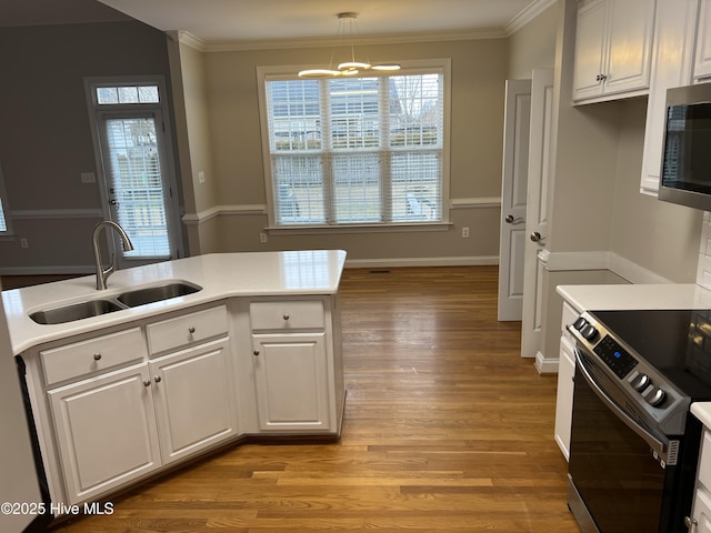 kitchen with stainless steel appliances, ornamental molding, a sink, and white cabinetry