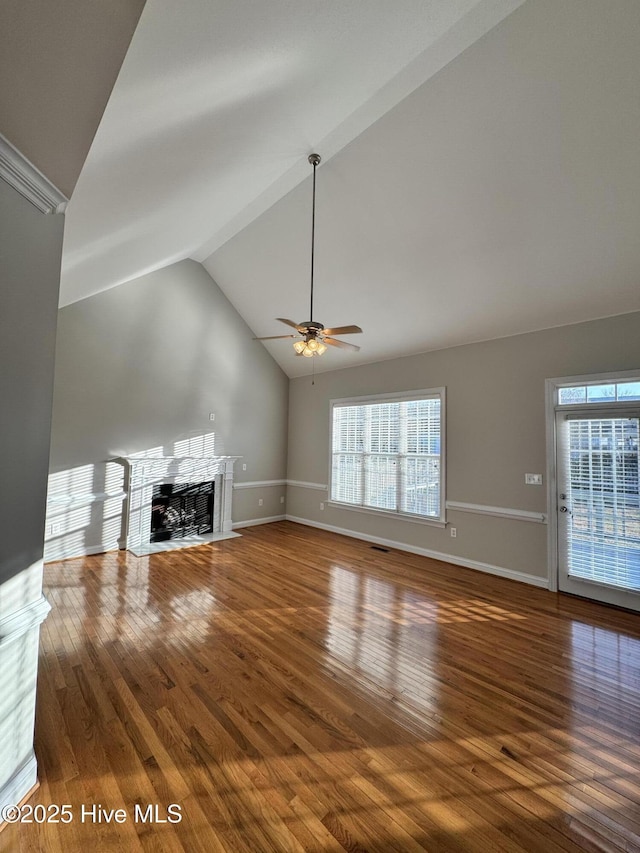 unfurnished living room with lofted ceiling, a fireplace with flush hearth, a ceiling fan, wood finished floors, and baseboards