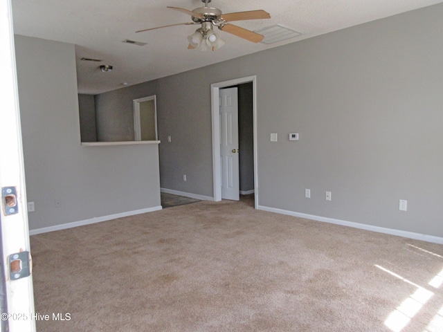 carpeted spare room featuring ceiling fan, visible vents, and baseboards