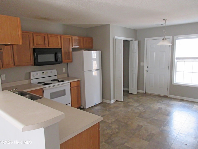 kitchen with pendant lighting, brown cabinets, light countertops, a sink, and white appliances