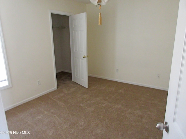 unfurnished bedroom featuring carpet, a spacious closet, baseboards, and a closet