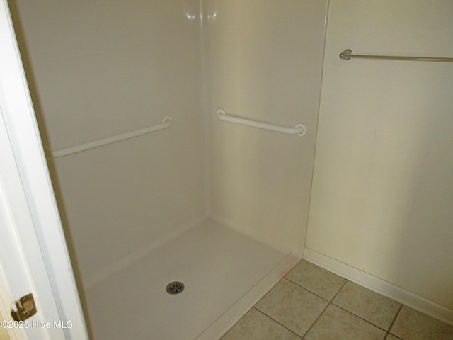 bathroom with baseboards, a shower, and tile patterned floors