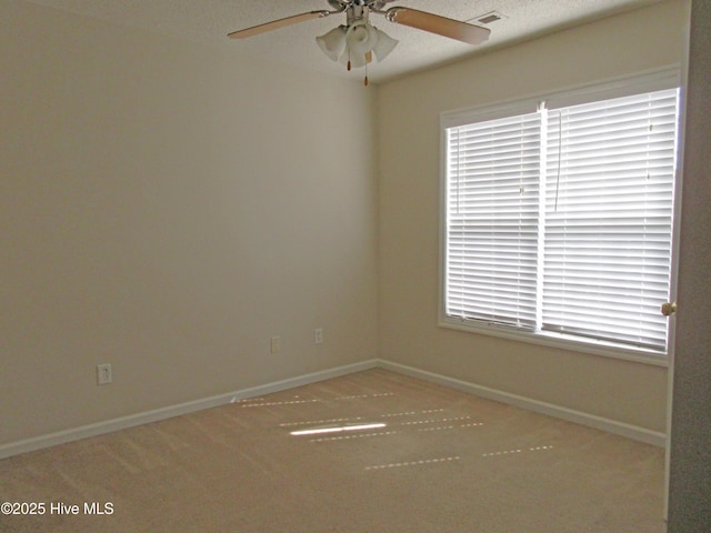 empty room with carpet floors, visible vents, ceiling fan, and baseboards