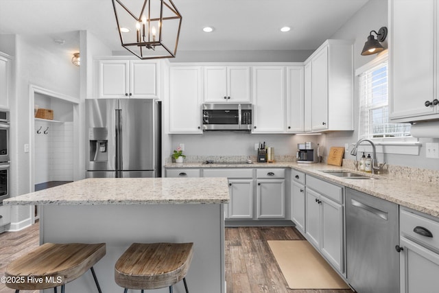 kitchen featuring a breakfast bar, a sink, white cabinetry, appliances with stainless steel finishes, and dark wood-style flooring