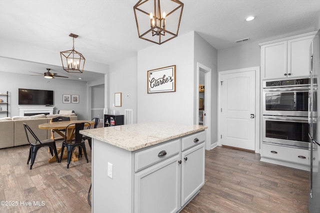 kitchen featuring decorative light fixtures, visible vents, double oven, and wood finished floors