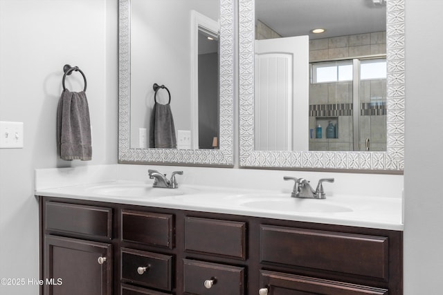 bathroom featuring double vanity, a shower with door, and a sink