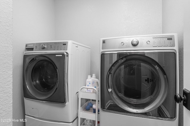 clothes washing area featuring laundry area, washing machine and dryer, and a textured wall