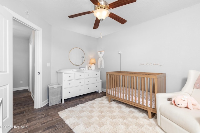 bedroom featuring baseboards, a ceiling fan, a nursery area, and wood finished floors