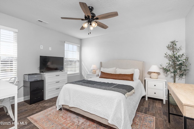 bedroom featuring baseboards, dark wood-style floors, visible vents, and ceiling fan