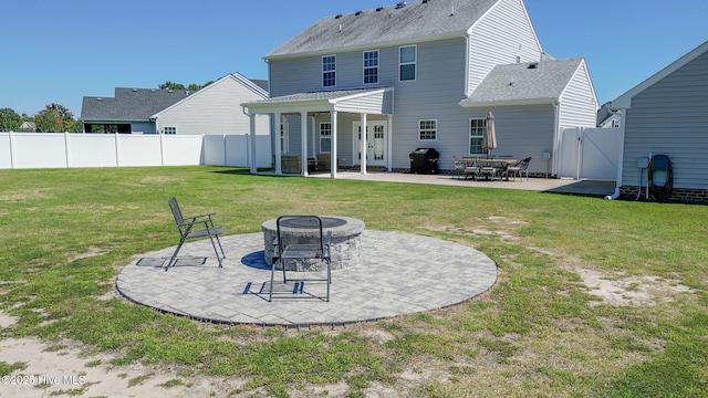 rear view of house with a patio, a gate, a fenced backyard, a fire pit, and a lawn