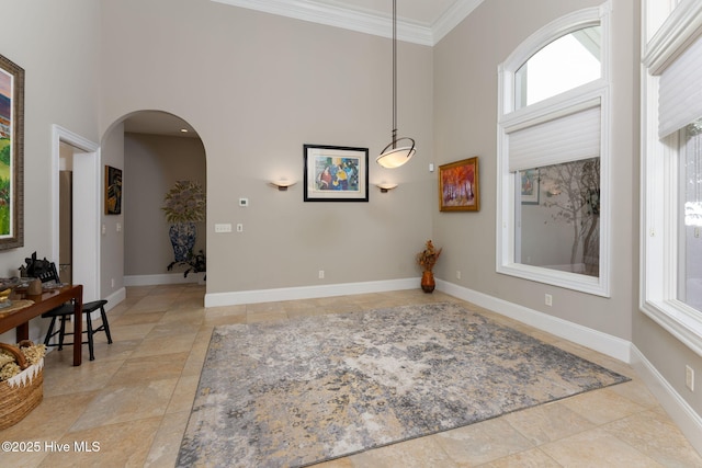 dining room with a towering ceiling, baseboards, arched walkways, and ornamental molding