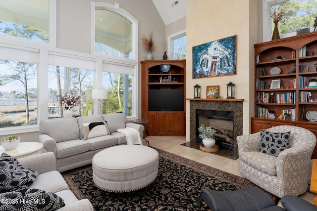 living area with built in features, a fireplace, a towering ceiling, and tile patterned floors