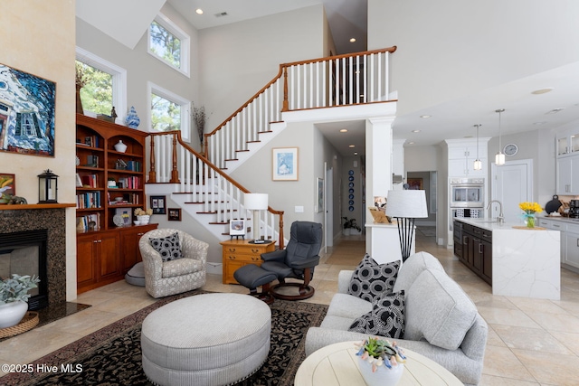 living area with recessed lighting, visible vents, a towering ceiling, a premium fireplace, and stairs