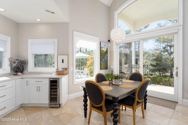 dining area with light tile patterned floors, recessed lighting, beverage cooler, visible vents, and baseboards