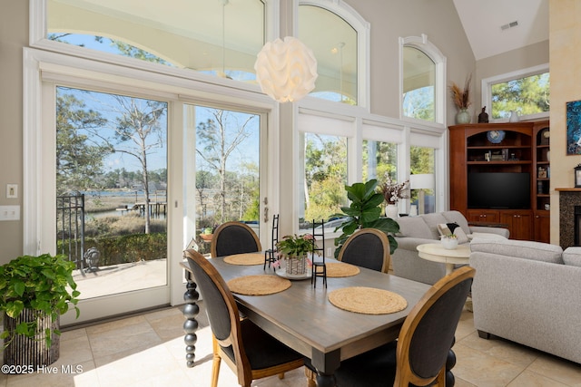 dining area featuring high vaulted ceiling, a healthy amount of sunlight, visible vents, and a fireplace