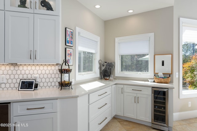 kitchen with a wealth of natural light, beverage cooler, light countertops, and decorative backsplash