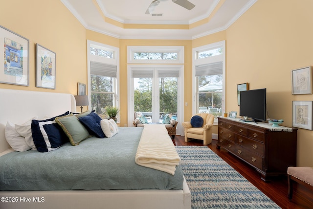 bedroom featuring a tray ceiling, visible vents, ornamental molding, and dark wood-type flooring