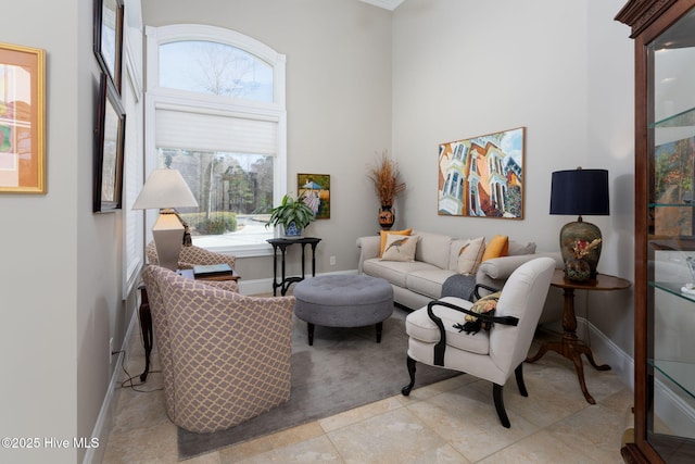 living room with a towering ceiling, baseboards, and tile patterned floors