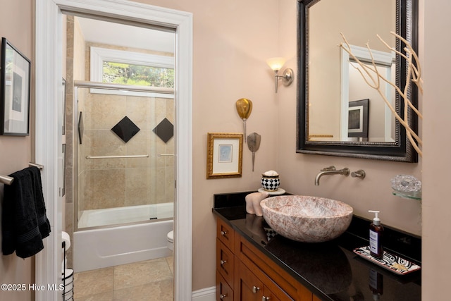 full bath with tile patterned floors, vanity, toilet, and bath / shower combo with glass door