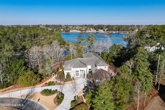 birds eye view of property featuring a water view and a wooded view