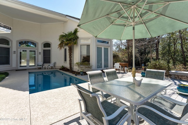 outdoor pool with outdoor dining space, a patio, and french doors