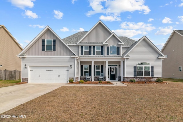 craftsman-style home with driveway, roof with shingles, covered porch, fence, and a front lawn