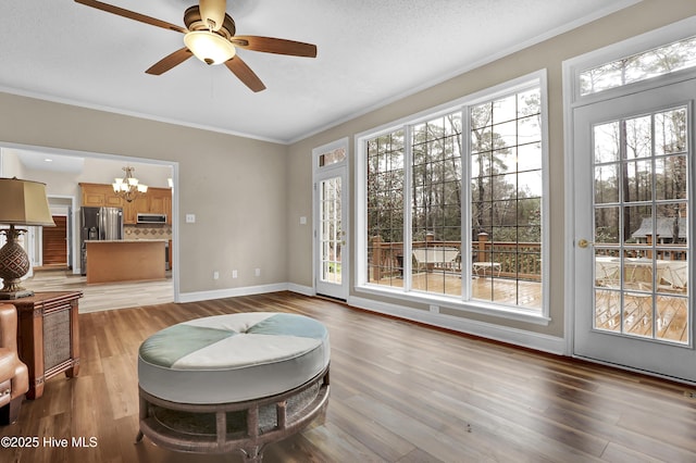 living area with crown molding, light wood-style flooring, and baseboards