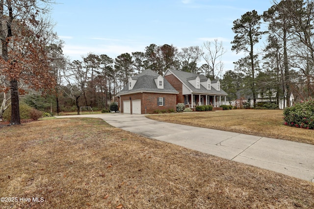 view of front facade with brick siding, covered porch, concrete driveway, a front yard, and a garage