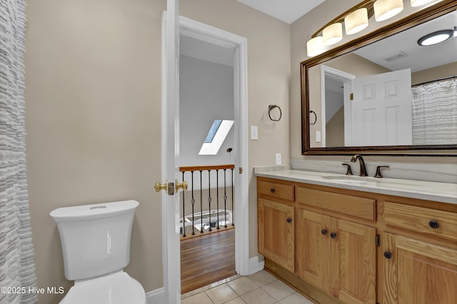 full bath with a skylight, visible vents, toilet, vanity, and tile patterned flooring