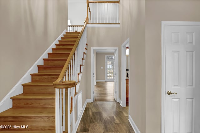 interior space with a towering ceiling, baseboards, and wood finished floors