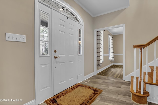 foyer with stairs, ornamental molding, wood finished floors, and baseboards