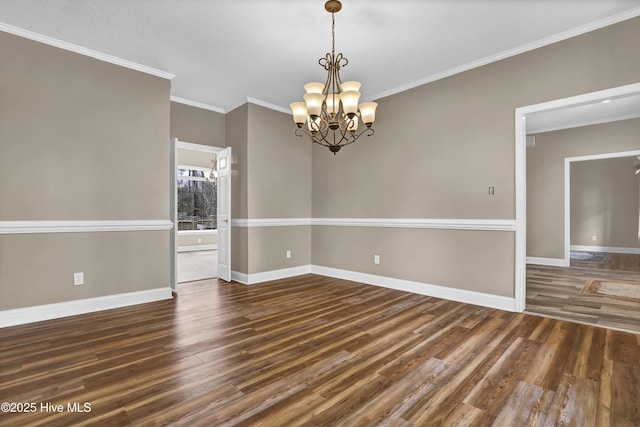 spare room featuring crown molding, a notable chandelier, baseboards, and wood finished floors