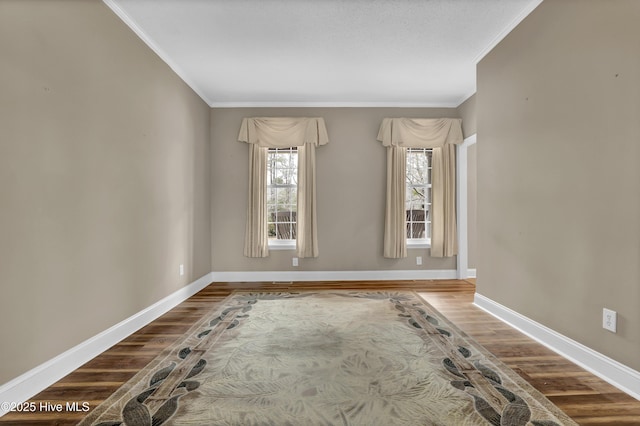 spare room featuring crown molding, baseboards, and wood finished floors