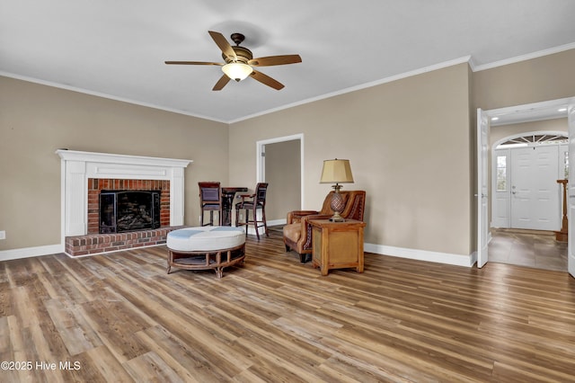 sitting room featuring light wood-style flooring, baseboards, and ornamental molding