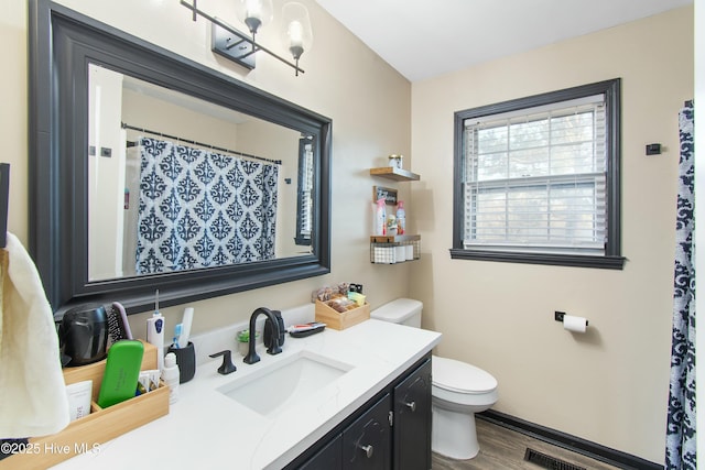 bathroom with toilet, wood finished floors, visible vents, vanity, and baseboards